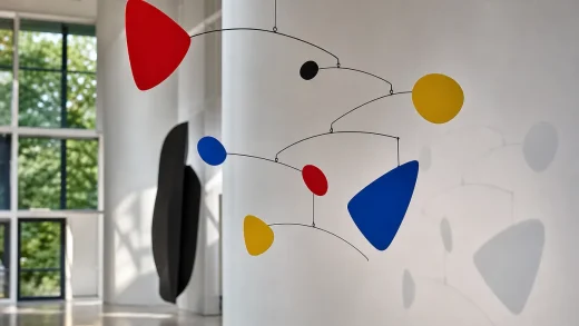 Abstrakt mobil av Alexander Calder hängande i konstgalleri med röda, blå och gula former